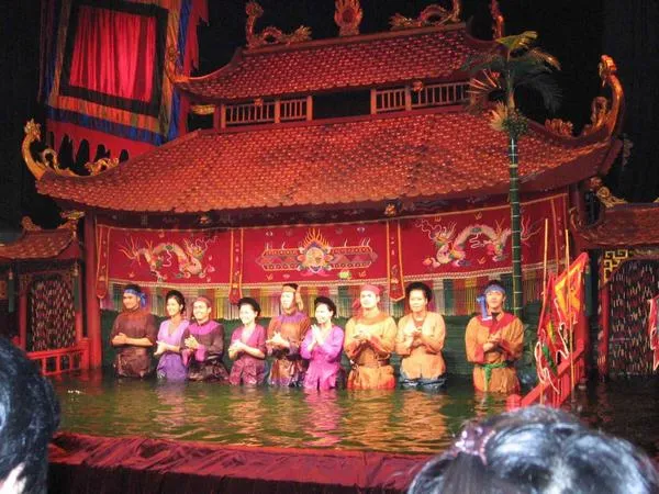 Bức ảnh múa rối nước thể hiện nghệ nhân điều khiển rối sau phông đình làng.