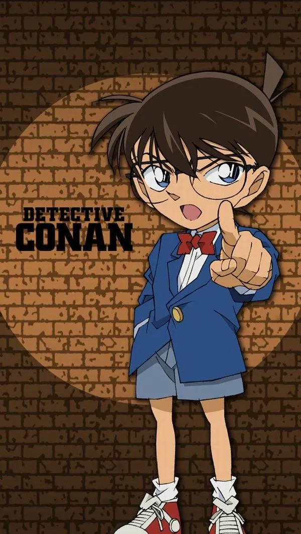 Ảnh Conan đứng trước tường gạch, áo vest xanh gọn gàng, vibe lạnh lùng kiểu tối giản