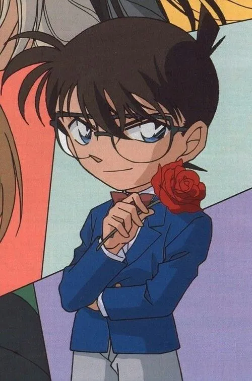 Ảnh Conan cài nút áo vest, nền đỏ cam rực, gương mặt nghiêm mà vẫn dễ thương