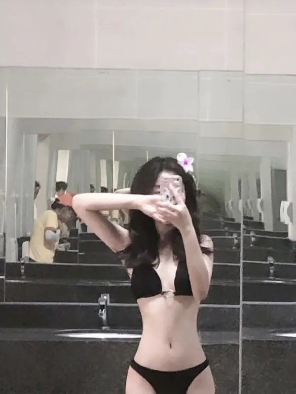 Cô nàng tạo dáng trên bậc thang, mặc bikini tối giản, một tay che mặt, vai trần mịn, ánh nhìn đầy thách thức.