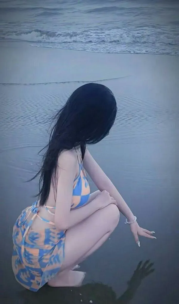 Nàng ngồi bên mặt nước, quay lưng, tóc rũ dài, bikini ôm dáng, vai trần mịn, vibe yên mà nóng.