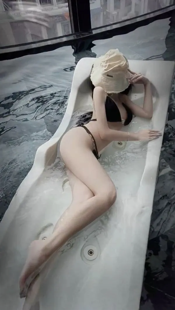 Nàng nằm thư giãn trên ghế, bikini tôn đường cong, tóc xõa, tay che mặt, da mịn, cảm giác lười biếng gợi.