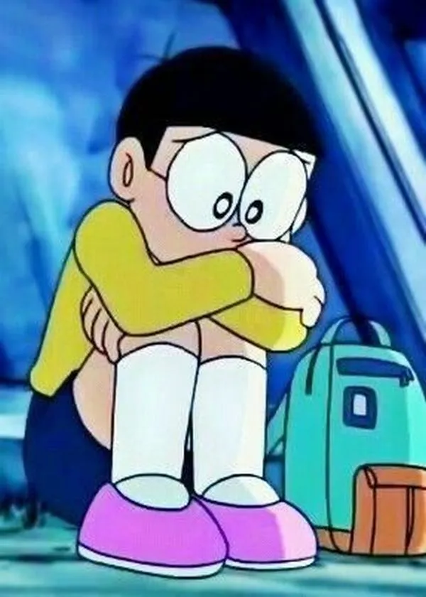 Nobita ôm gối ngồi co ro, mắt nhìn xuống, cô đơn như bị cả lớp bỏ quên.