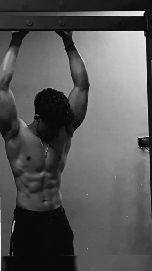 Treo xà trong phòng gym, cơ bụng nổi rõ, dáng tập nghiêm túc và kỷ luật.