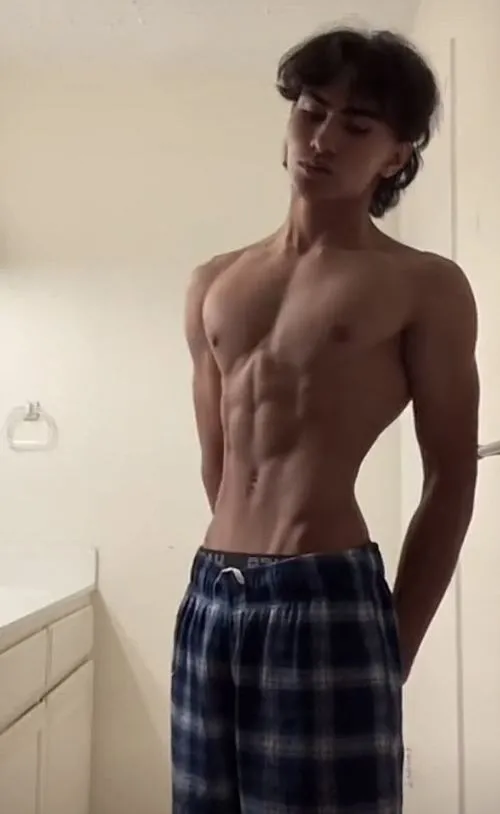 Đứng cạnh tường, body nam săn chắc, ánh sáng xiên tạo bóng đổ trông rất cuốn.