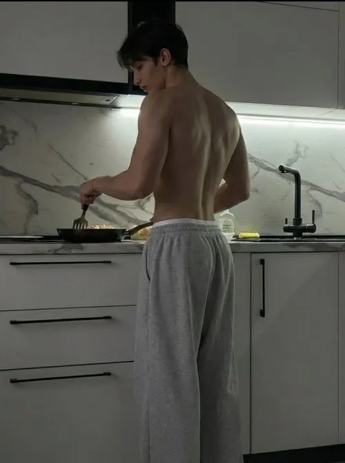 Dáng đứng trong bếp, lưng trần nhìn gọn, cảm giác đời thường mà vẫn nam tính.