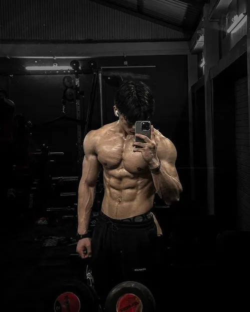 Ánh sáng studio chiếu xiên, cơ bụng nổi khối, tông trầm làm ảnh trông nghệ thuật.