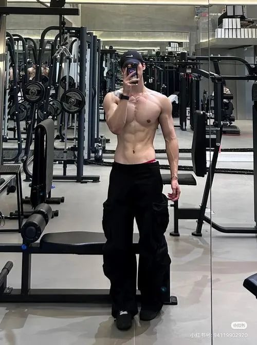 Soái ca cơ bụng chụp trong phòng gym, thân trên dày, pose thả lỏng mà vẫn có lực