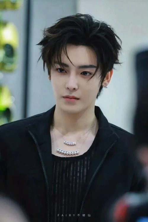 Trai chất ngoài trời, hậu cảnh mờ, tóc dựng nhẹ và mắt nhìn xa như đang chờ ai.