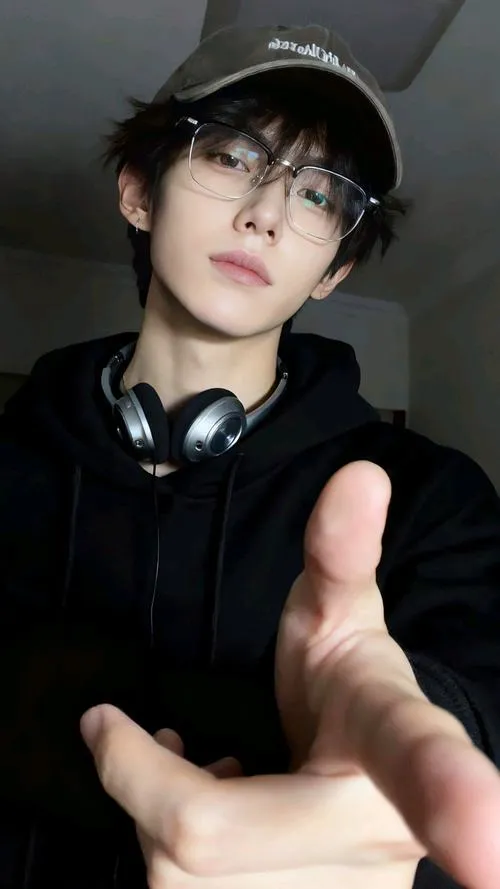 Trai phong trần hoodie, biển hiệu mờ phía sau, ánh đèn hắt làm mắt càng trầm.