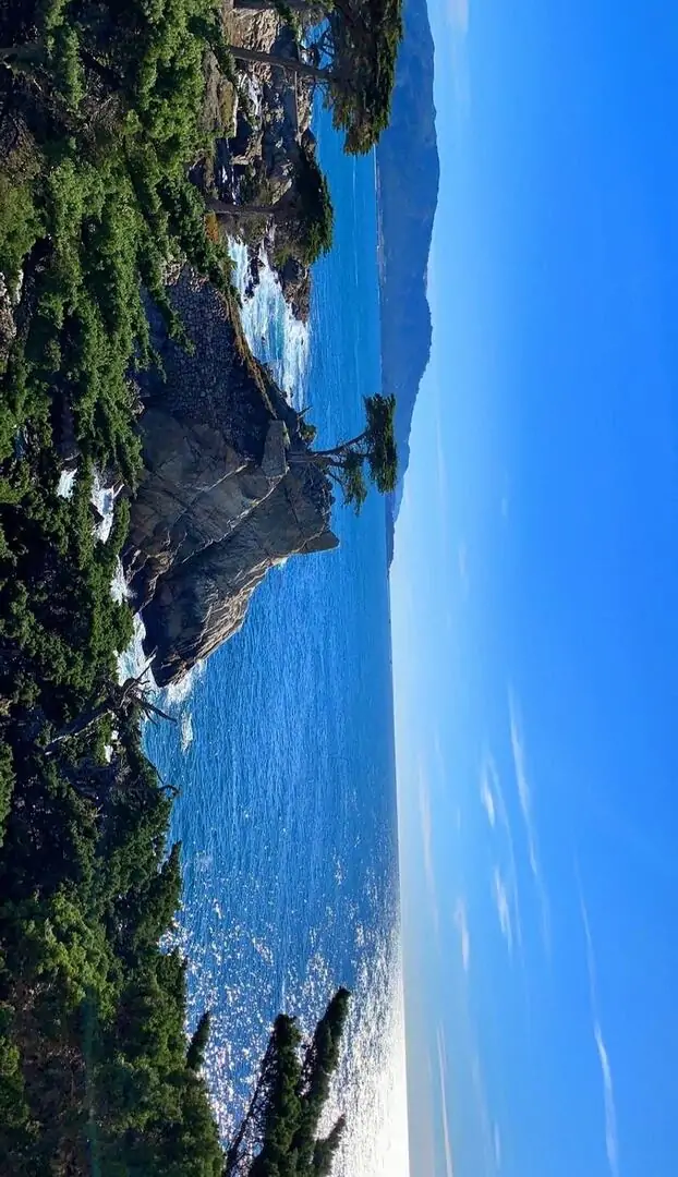 Vịnh biển xanh ngắt ôm quanh các vách núi đá, mặt nước trong và đường bờ cong mềm khiến khung cảnh này hợp làm ảnh nền thiên nhiên cho ngày nắng