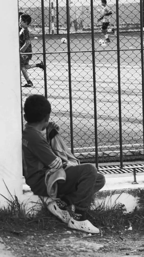 Ảnh wallpaper đen trắng về một cậu bé ngồi lặng lẽ bên hàng rào gợi nhắc niềm đam mê túc cầu cháy bỏng với độ sâu trường ảnh đầy tâm trạng.