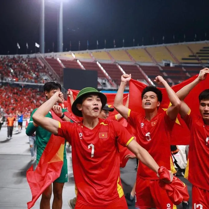 Khung hình chân dung một cầu thủ trẻ đang nhìn lên khán đài với ánh mắt đầy biết ơn, cảm nhận hơi ấm từ người hâm mộ bóng đá cả nước