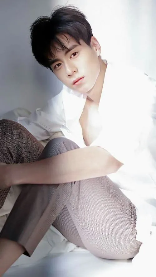 Khoảnh khắc hotboy áo trắng chụp cận gương mặt bên khung cửa sáng, ánh mắt nhìn thẳng và cánh tay đặt phía trước.