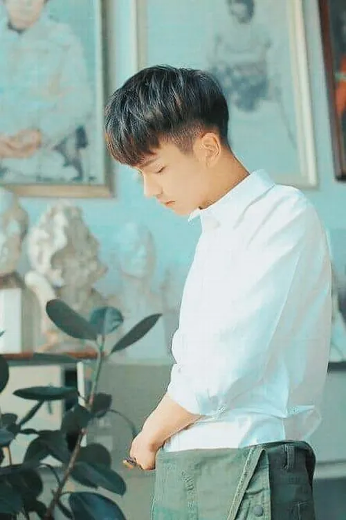 Nam giới mặc sơ mi trắng bước qua sảnh kính, độ rủ của vải hiện rõ khi tay cầm tập hồ sơ mỏng.