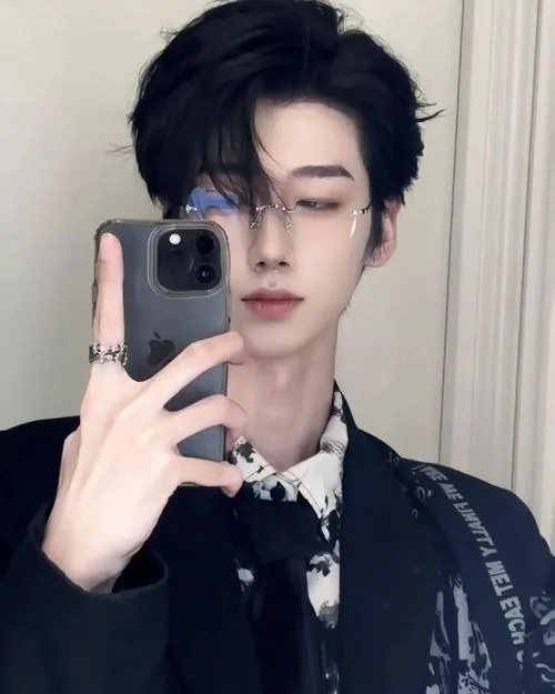 Chàng trai tóc đen chụp selfie trước gương, áo blazer tối màu và cổ áo trắng tạo diện mạo trẻ trung, gọn gàng.