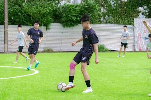 Một chàng trai mặc áo thủ môn ôm găng tay trước khung gỗ cũ, mặt sân đất đỏ tạo cảm giác rất mộc.