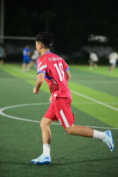 Chàng trai đứng trước bảng chiến thuật của ban huấn luyện, mắt nhìn sơ đồ chuyền bóng với vẻ chăm chú.
