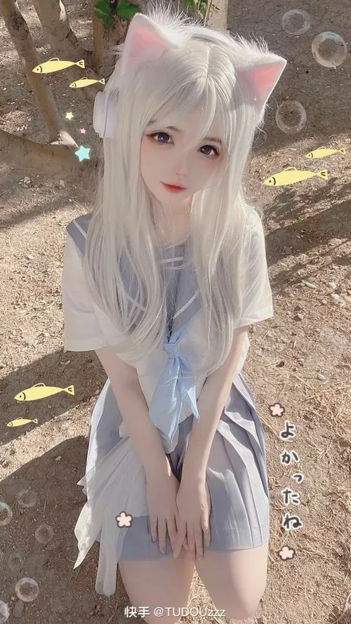 Ảnh gái xinh cosplay mèo với mái tóc trắng dài, áo thun rộng và góc chụp từ trên xuống làm gương mặt thêm trong trẻo.