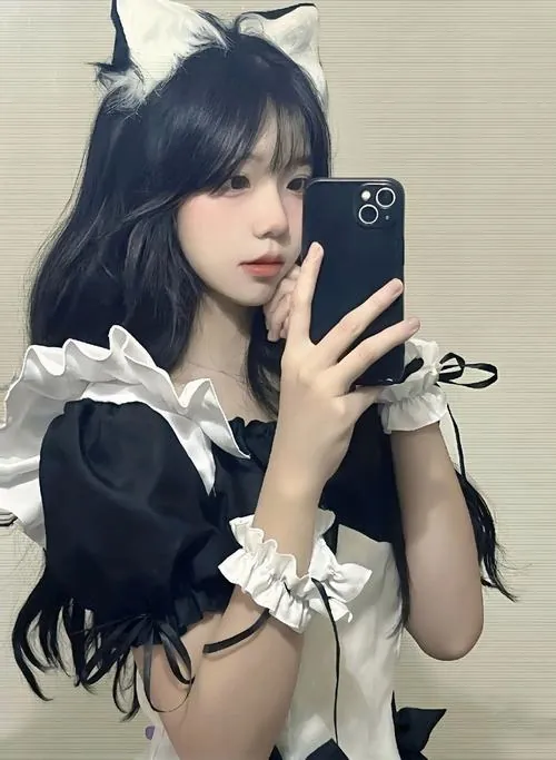 Ảnh gái xinh cosplay mèo tóc đen chụp selfie trước gương, tay cầm điện thoại che một phần gương mặt xinh xắn.