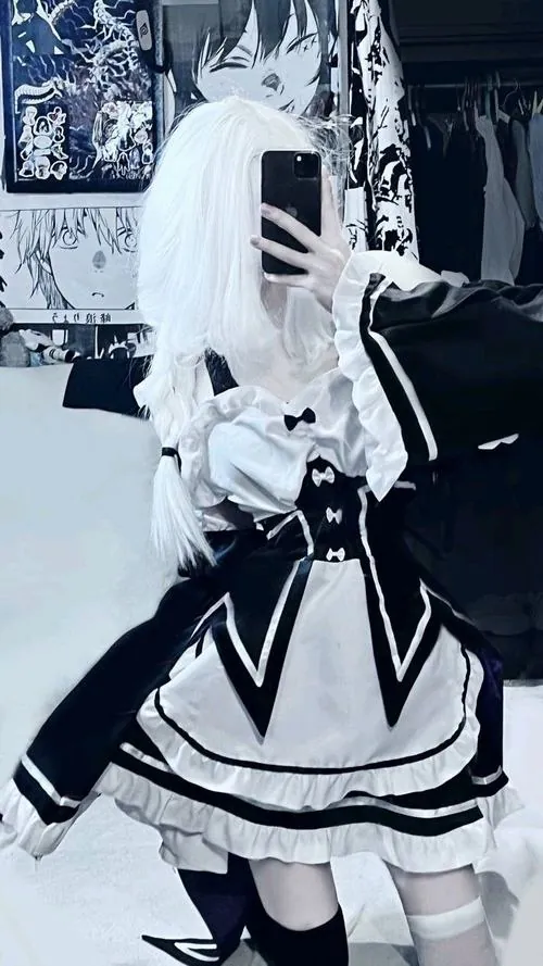 Ảnh gái xinh cosplay mèo mặc trang phục đen trắng, phần váy xếp tầng và dáng đứng nghiêng tạo cảm giác tinh nghịch.