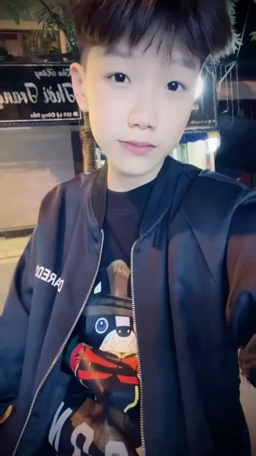 Ảnh trai đẹp k9 mặc áo khoác xanh đậm, selfie trong nhà với nụ cười nhẹ và gương mặt trắng sáng.