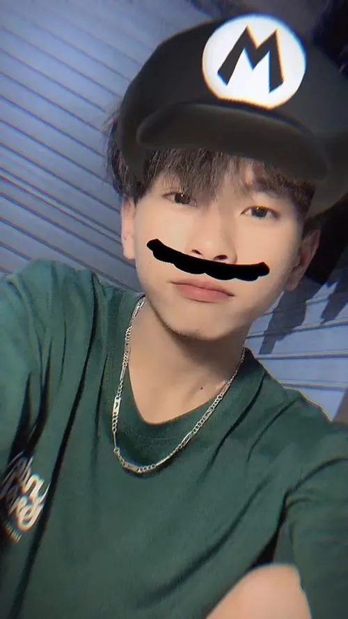 Nam sinh áo xanh dùng filter ria mép, tóc mái gọn và nụ cười nhẹ khiến ảnh selfie có nét tinh nghịch.