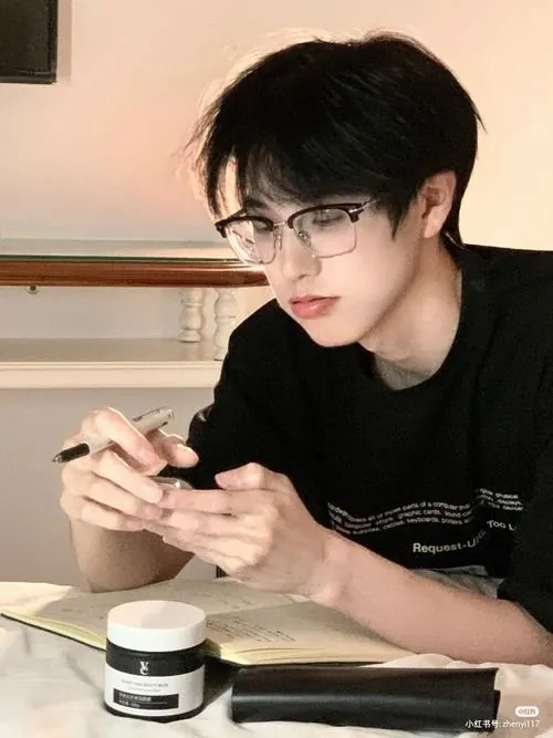 Buổi sớm mưa nhẹ, một bạn nam cầm ô đứng chờ xe buýt, đồng phục còn vương nước nhưng nụ cười vẫn háo hức.
