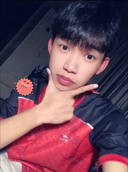 Bạn nam mặc áo thể thao đỏ đen tạo dáng tay chữ V, nụ cười tươi giúp khung ảnh sáng và vui hơn.