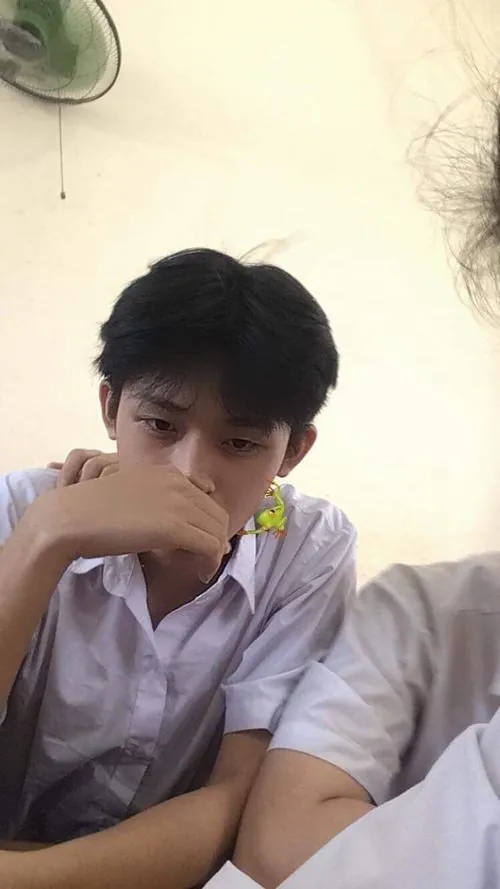 Giờ ra chơi trên sân trường, nam sinh lớp 7 mặc áo thể dục nâng quả bóng rổ ngang mặt, ba lô đặt cạnh ghế đá.