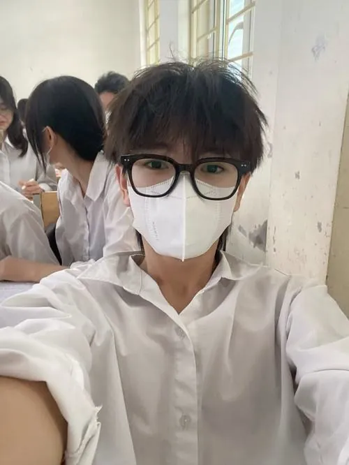 Trên sân tập buổi chiều, một bạn nam mặc đồng phục thể thao quay lưng về ống kính, chiếc mũ lưỡi trai kéo thấp.