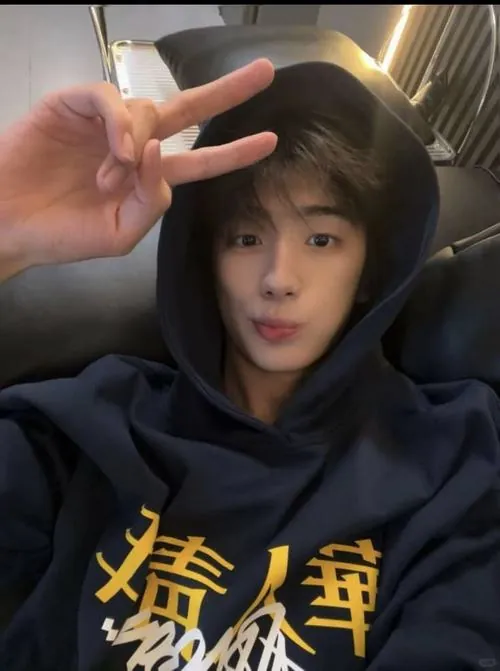 Ảnh cậu bạn cùng bàn đẹp trai mặc hoodie đen, giơ tay chữ V trước ống kính với biểu cảm ngơ ngác rất dễ mến.