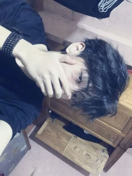 Bức ảnh nam giấu mặt bằng tay được chụp từ góc nghiêng với bàn tay đưa lên che kín một bên mắt, làm nổi bật đường nét sống mũi cao cùng mái tóc đen rủ tự nhiên.
