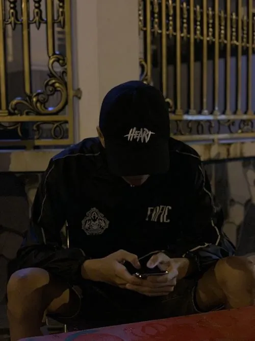 Chàng trai trượt ván dừng lại bên con hẻm graffiti, kéo chiếc mũ bảo hiểm sụp xuống che mắt trong khi tay vẫn ôm chiếc board.