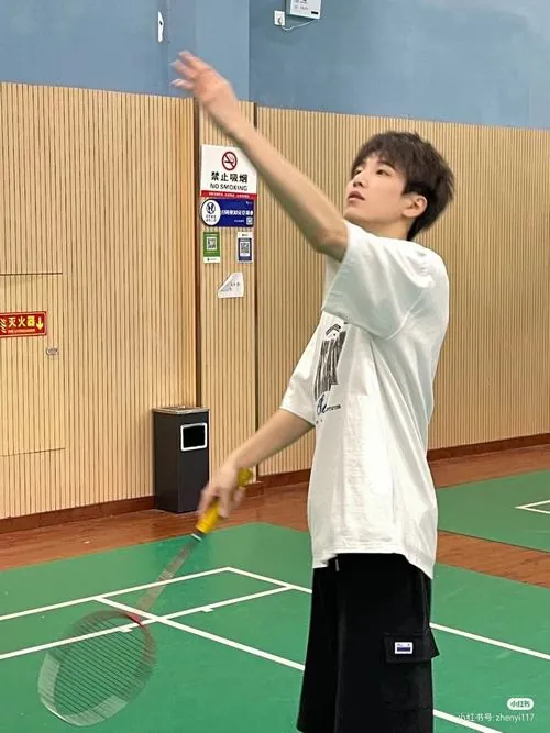 Hot boy thể thao mặc áo phông trắng đưa tay lên cao chuẩn bị thực hiện cú phát cầu uy lực qua lưới.