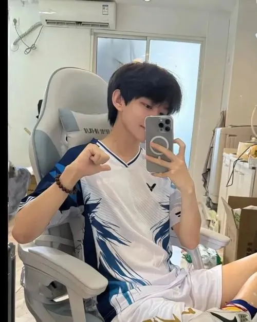 Chàng trai ngồi selfie trước gương phòng tập, tay giơ ký hiệu vui vẻ trong bộ trang phục thi đấu trẻ trung.